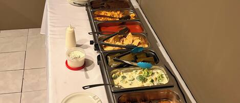 A buffet table with various food items and utensils.