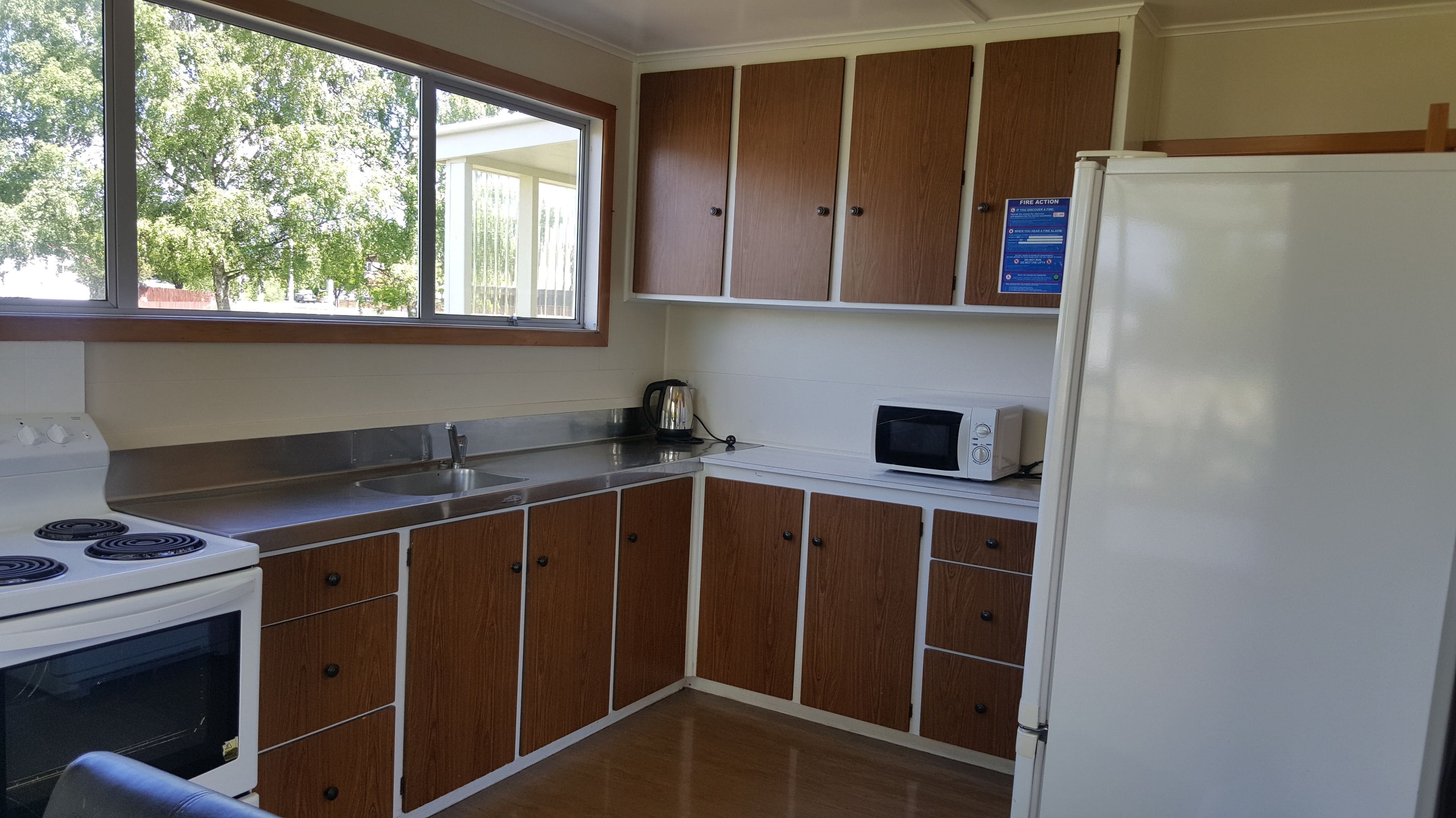 A kitchen with wooden cabinets, a white stove, a microwave, and a refrigerator.