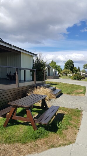 A picnic table and benches in front of a building with a covered deck. - High Country Motel and Backpackers (Twizel)