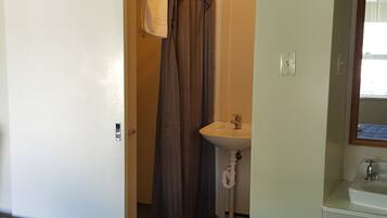 Une chambre d’hôtel avec un lit, une salle de bain comprenant un lavabo et un miroir, et une fenêtre.