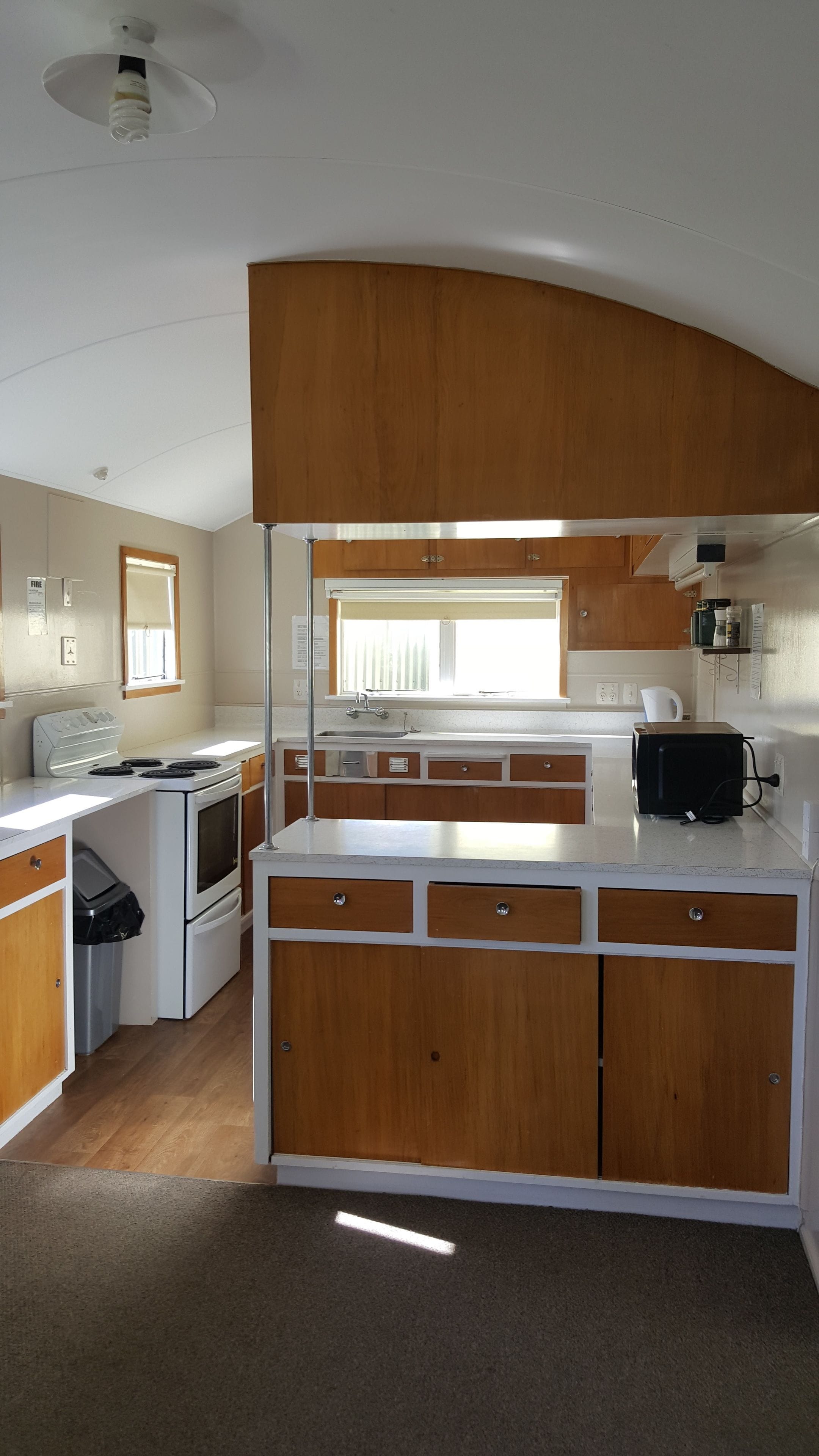 A compact kitchen with wooden cabinets, a white stove, and a black toaster.