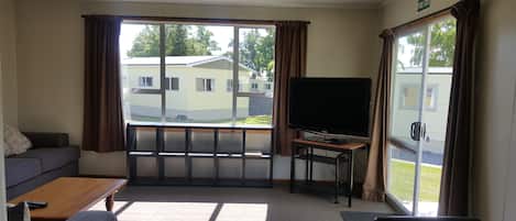 Quarto com uma grande janela, televisão de tela plana, sofá e mesa.