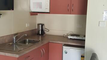 A compact kitchen with a microwave, a coffee maker, and a dishwasher.
