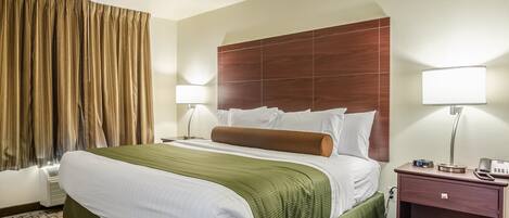 A hotel room with a large bed, a wooden headboard, two bedside lamps, a nightstand with a phone and a BJD clock, and a window with curtains.