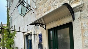 A stone building with a green door, a small garden, and a metal gate.