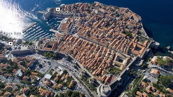 Luchtbeeld van een kustplaats met een opvallend fort, Place Gate, en een jachthaven.