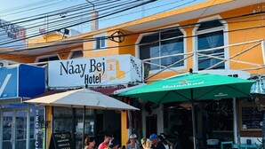 Ein Hotel namens "Náay Bei Hotel" mit Außenbestuhlung und einem grünen Sonnenschirm.