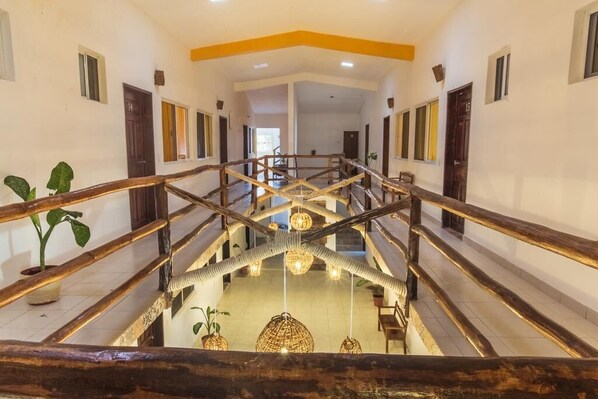 A multi-level interior with wooden railings, a central staircase, and hanging spherical light fixtures. - Naay Bej (Tulum)
