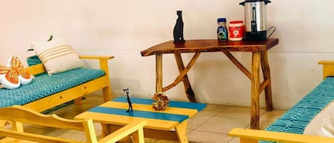 A compact living space with a sofa, two small tables, and a coffee maker.
