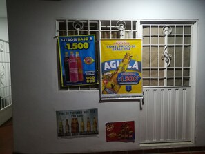 Dos carteles promocionales en una pared, junto a una ventana con barrotes.