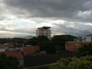 Zona residencial con una mezcla de edificios modernos y tradicionales, destacando un edificio principal de varios pisos con techo plano y una estructura más pequeña contigua.