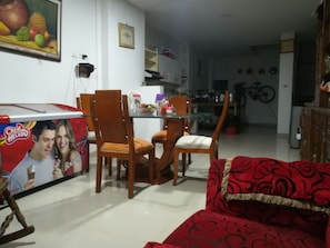 Un comedor con una mesa de vidrio, sillas de madera y un sofá rojo.