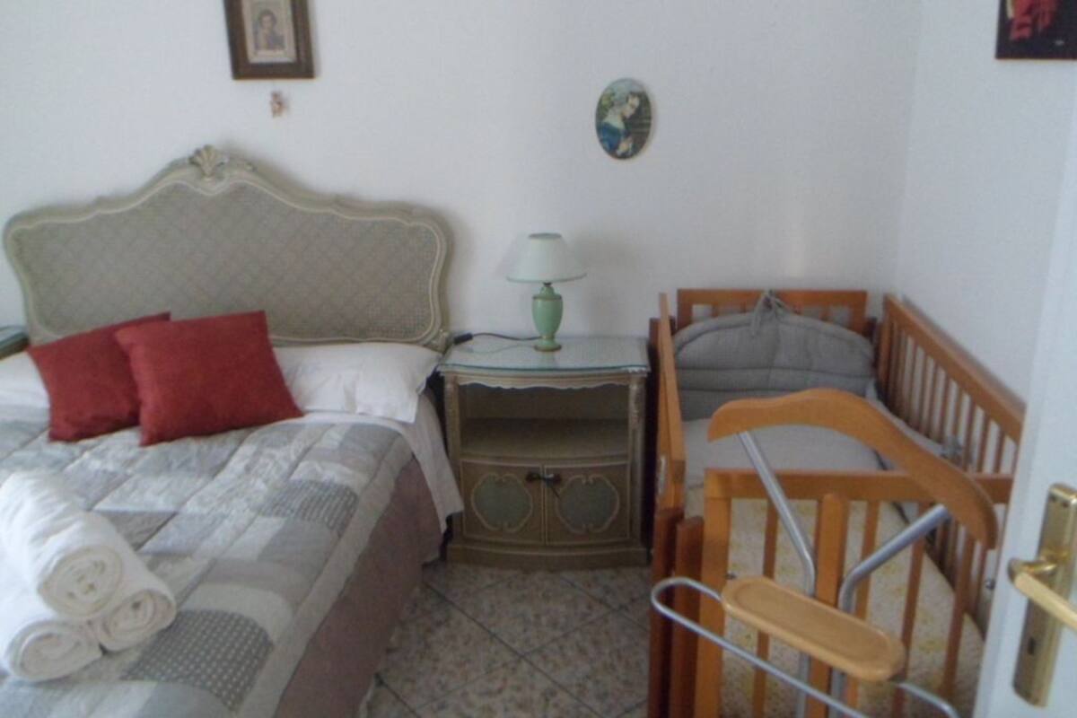 Une chambre à coucher comprenant un lit, une table de chevet, une chaise et une petite table avec une lampe.