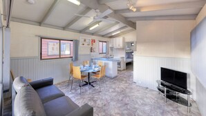 Un espace de vie compact comprenant un coin repas, une kitchenette et un téléviseur.