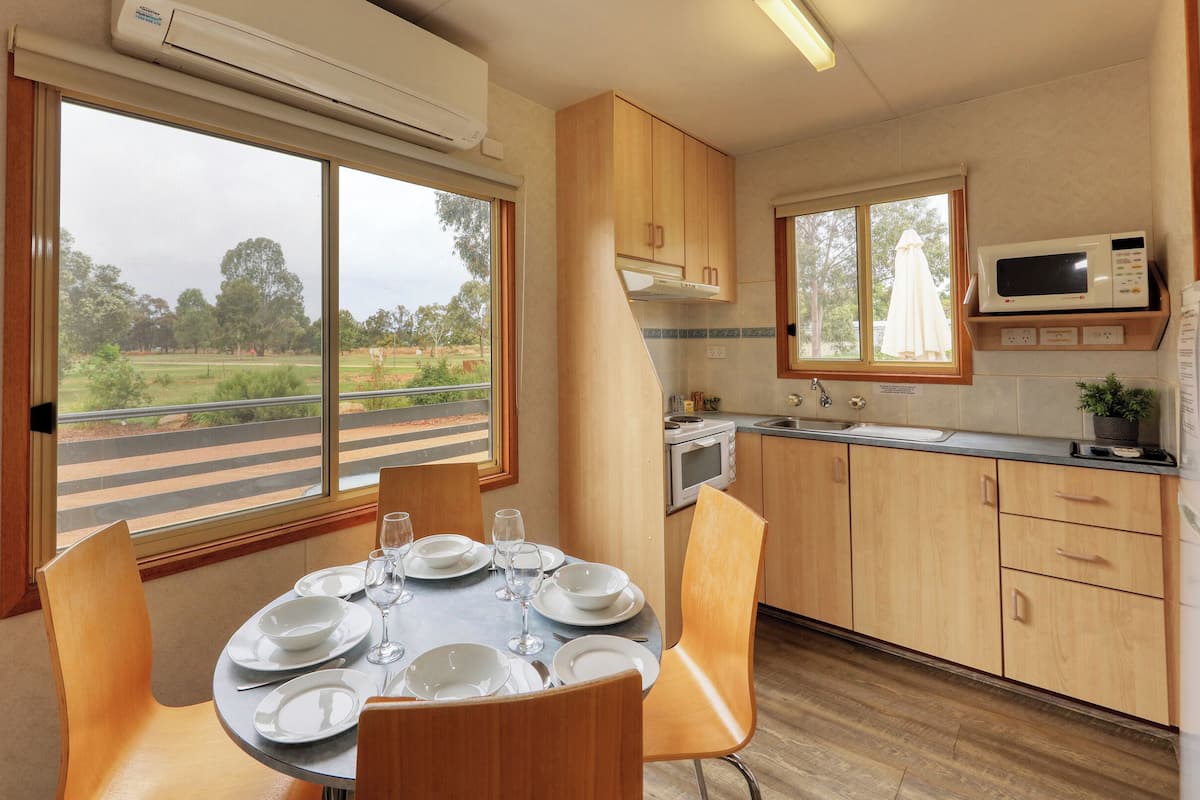 Une cuisine compacte avec un coin repas, comprenant une table pour quatre personnes, un four à micro-ondes et un évier.