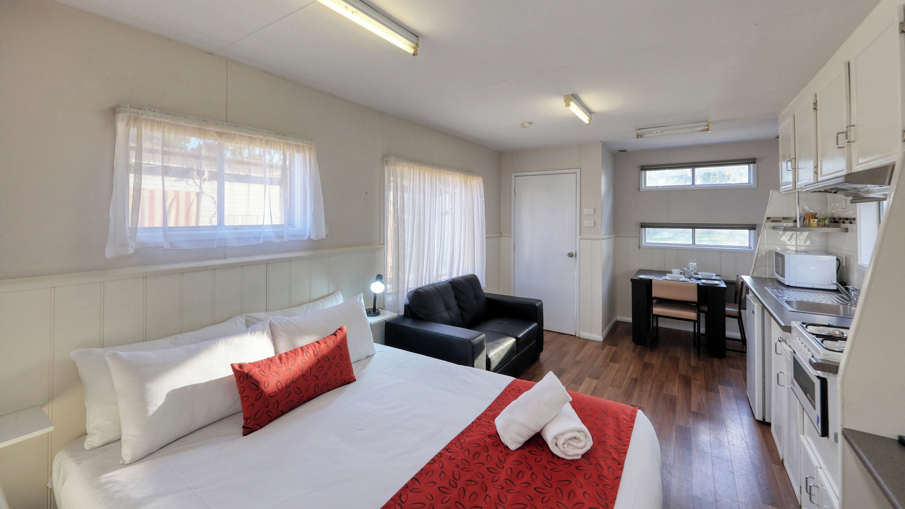 Ett hotellrum med en säng, ett skrivbord, en stol, en soffa och ett litet kök.