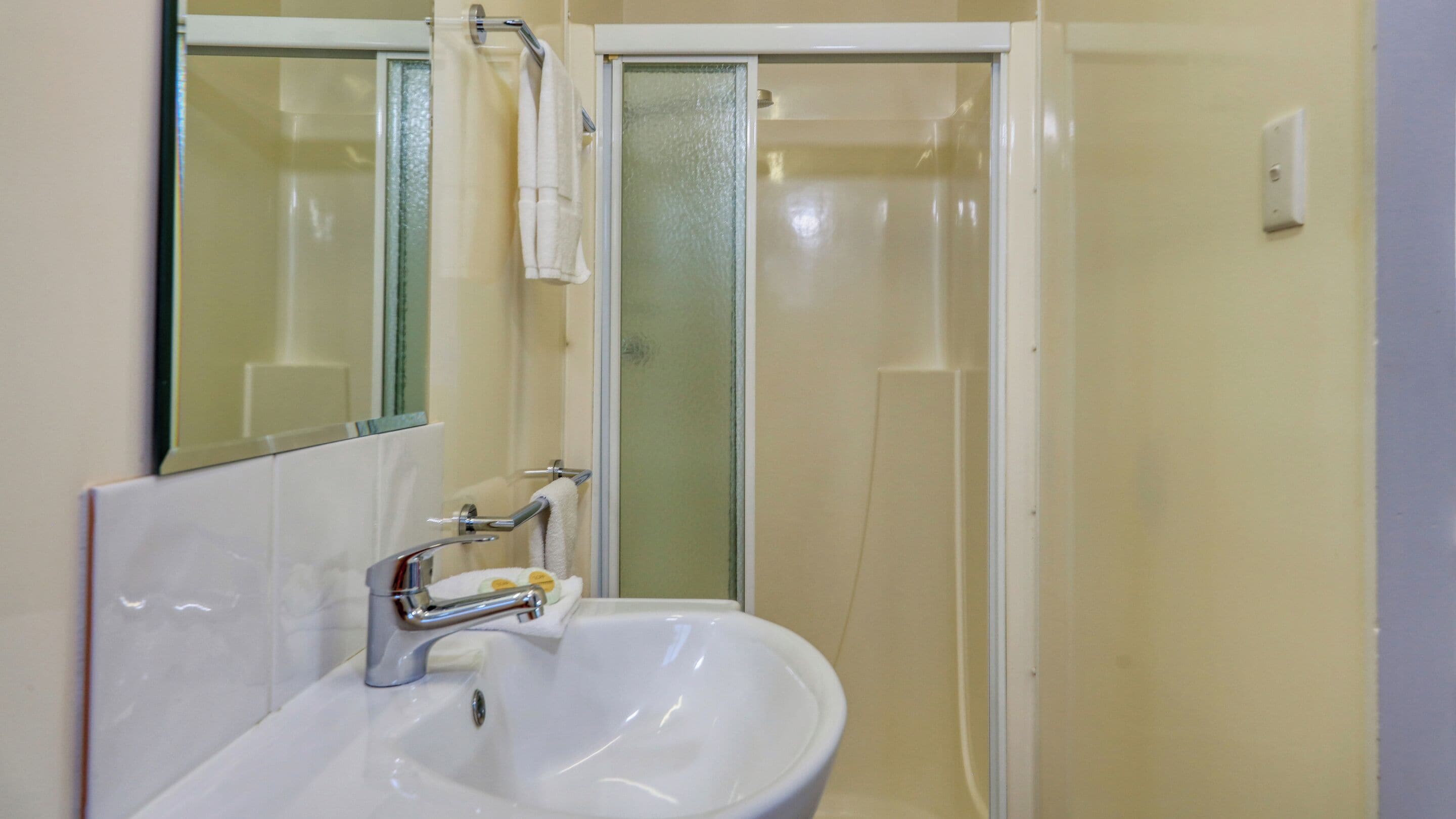 A bathroom with a white sink, a mirror, and a glass shower door.
