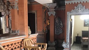 A room with a traditional wooden sofa, a tiled floor, and ornate wall decorations. - Kacu guest house (Ubud)