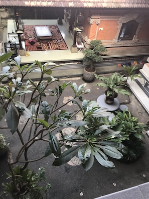 Un patio con plantas en macetas, una pequeña mesa y una estatua.