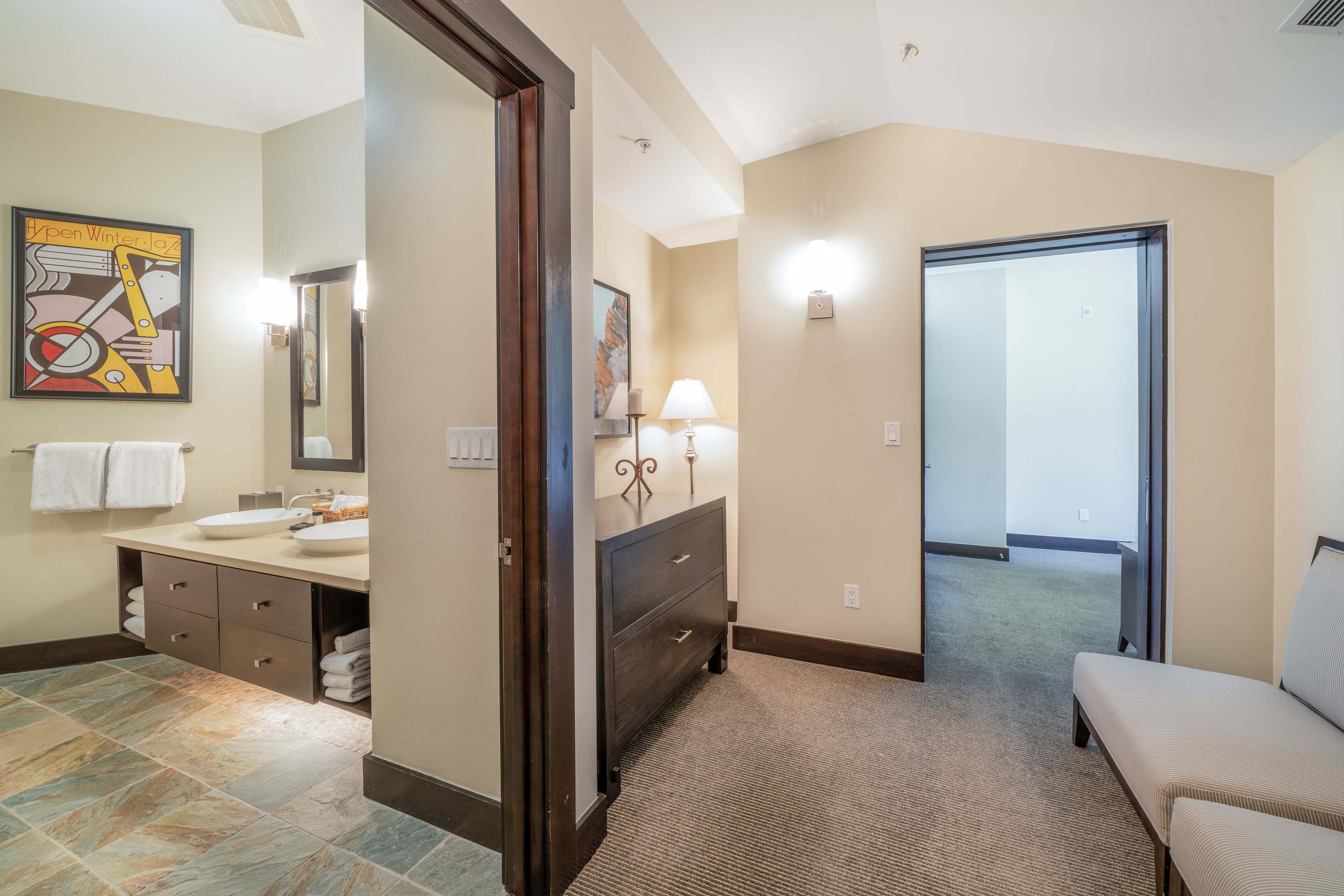 A bathroom with a sink, mirror, towel rack, and a painting on the wall.