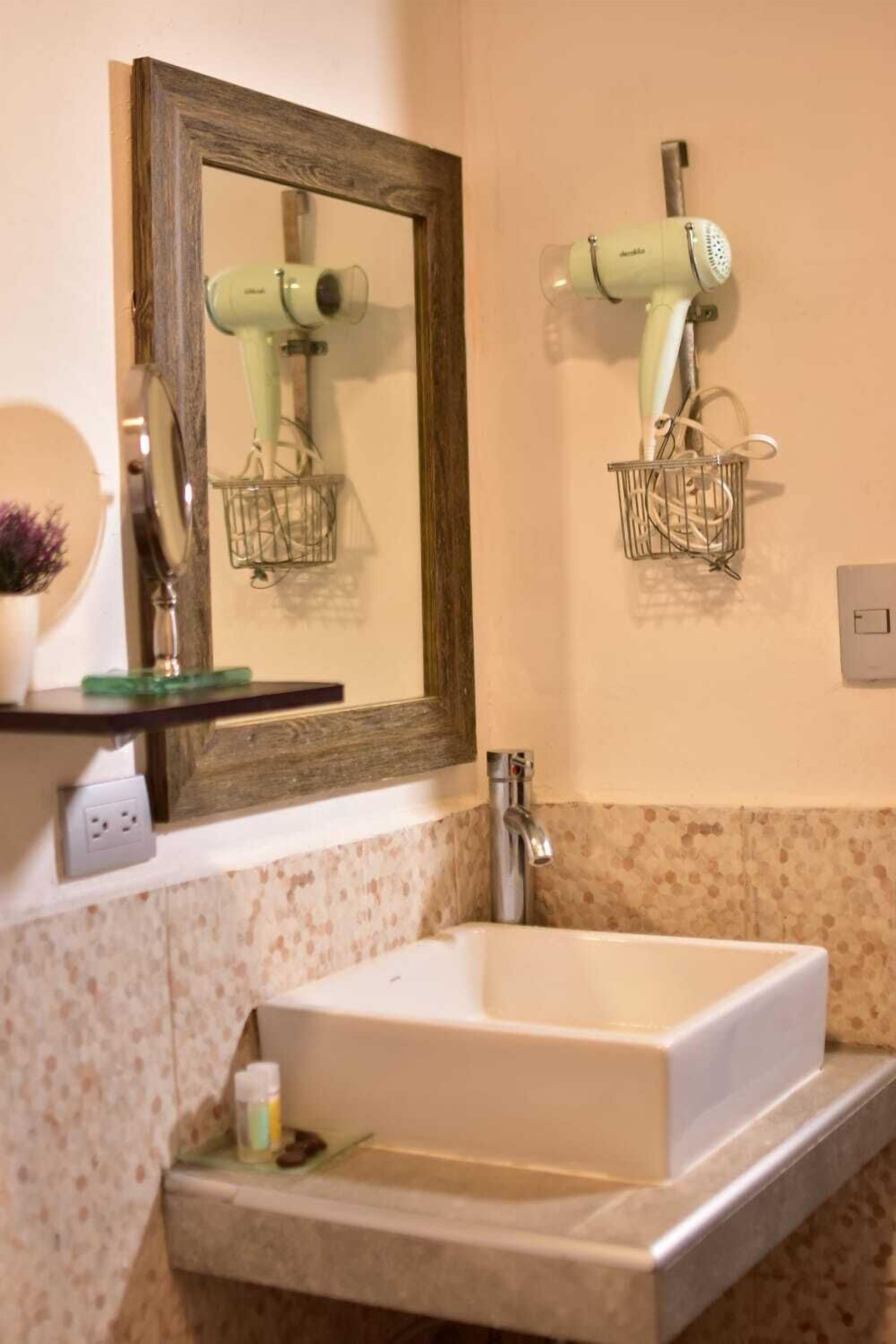 A bathroom with a large mirror, a white sink, and two hair dryers mounted on the wall.