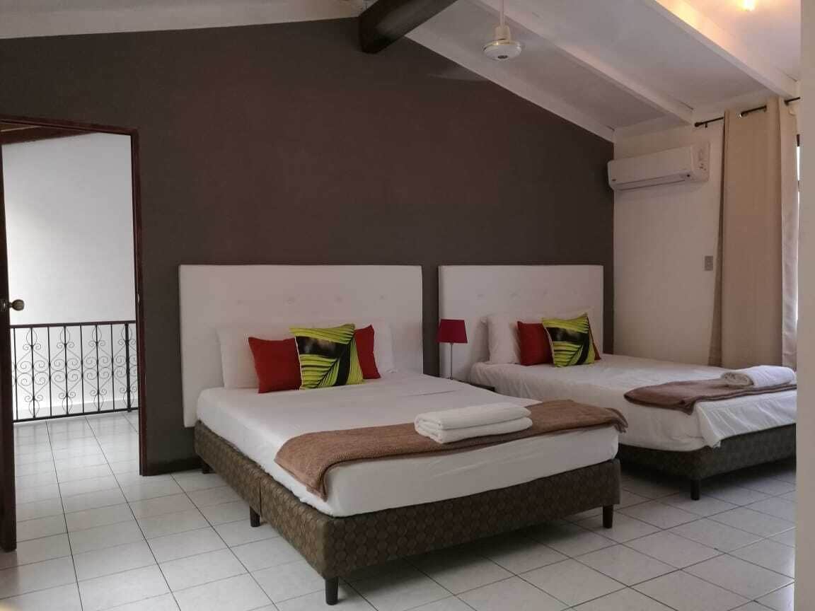 A hotel room with two beds, a large window, and a door leading to a balcony.
