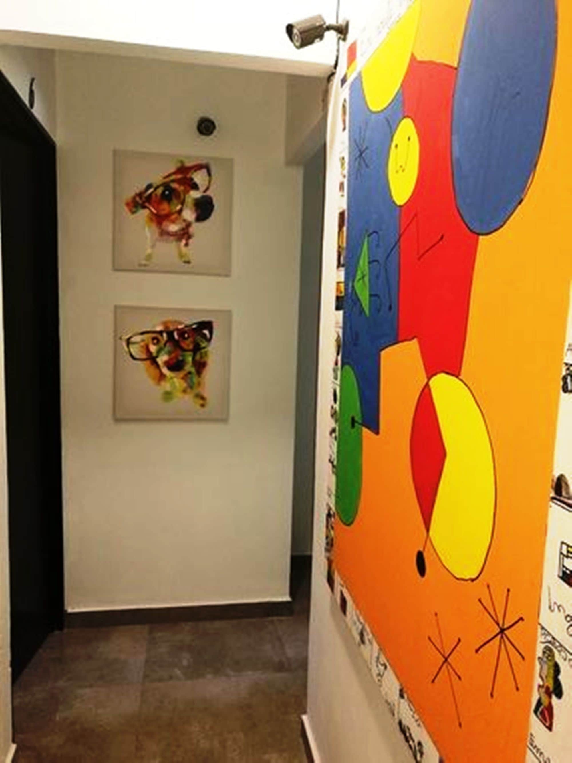 A hallway with two framed artworks on the wall and a colorful mural on the adjacent wall.