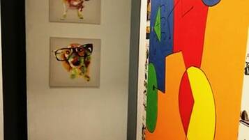A hallway with two framed artworks on the wall and a colorful mural on the adjacent wall.