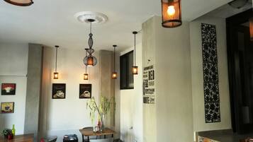 Un comedor moderno con lámparas colgantes, una mesa central con sillas y una pared decorativa con texto y diseños.