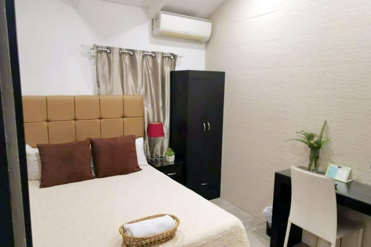 Ein ordentlich eingerichtetes Schlafzimmer mit einem Bett, einem Schreibtisch und einem Kleiderschrank.