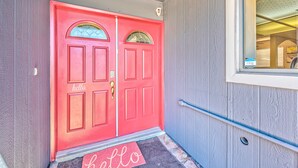 Unas puertas dobles rojas con un felpudo que dice 'hello' en la entrada.