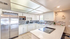 Una cocina moderna con armarios blancos, electrodomésticos de acero inoxidable y una isla grande con estufa integrada.