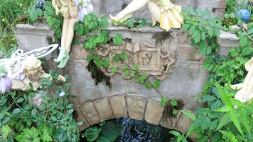 A garden with a stone bridge, fairy statues, and lush greenery.