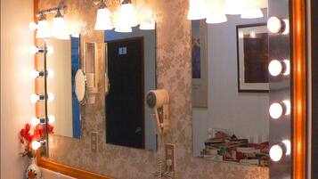 A bathroom with a large mirror, multiple lights, and two sinks.