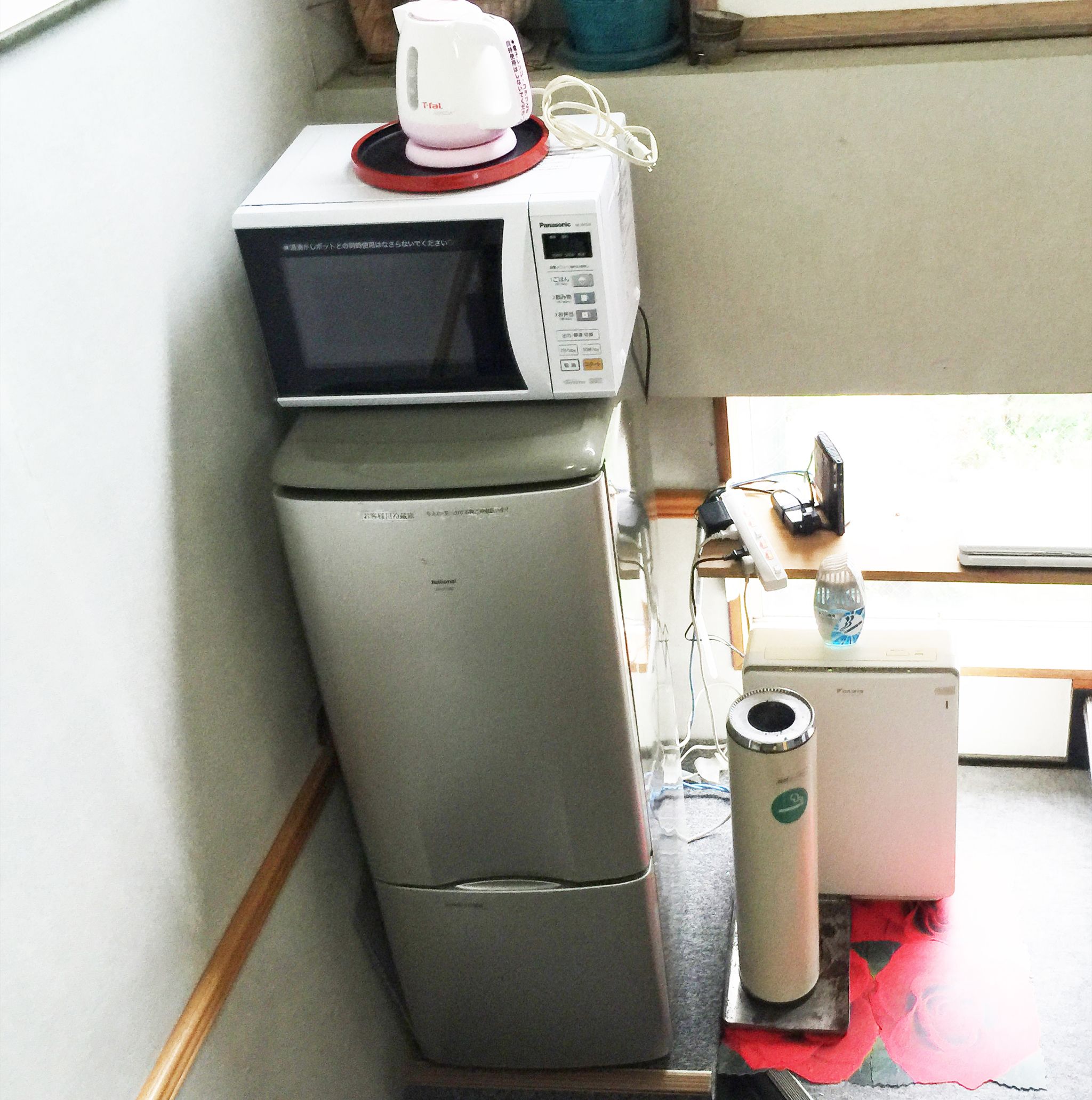 A compact kitchen with a microwave, refrigerator, and a small water dispenser.