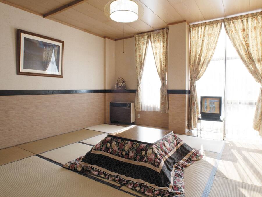 Una habitación japonesa tradicional con suelo de tatami, una mesa baja, un televisor y un cuadro en la pared.