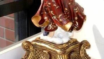 A statue of an angel holding a golden lamp, standing on an ornate base.