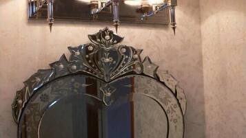 A heart-shaped mirror with a decorative frame and three wall-mounted lamps above it.