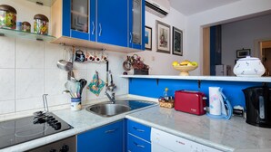 A modern kitchen with blue cabinets, a stainless steel sink, a Bosch dishwasher, and a red toaster. - Comfortable and fully furbished apartment in center (Split)