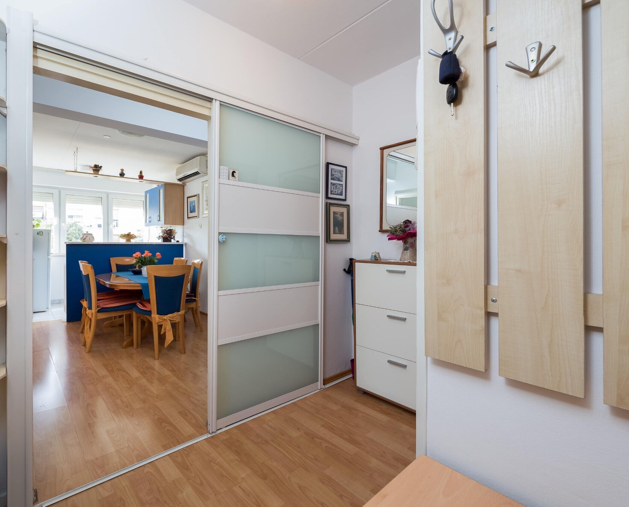 A room with a sliding door leading to a dining area, a wooden cabinet with a mirror, and a small table with a vase. - Comfortable and fully furbished apartment in center (Split)