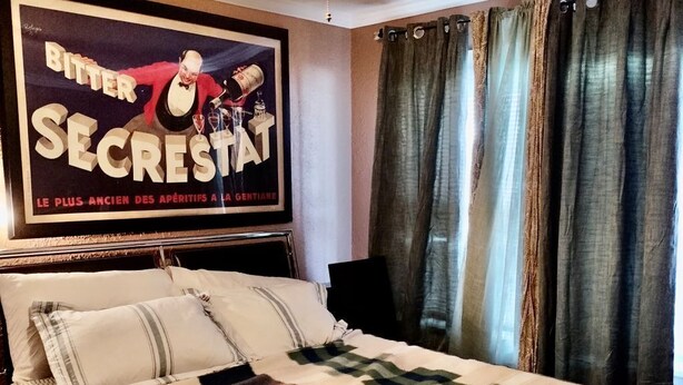 Ein Schlafzimmer mit einem Bett, einem Deckenventilator, einem Poster an der Wand und Vorhängen.
