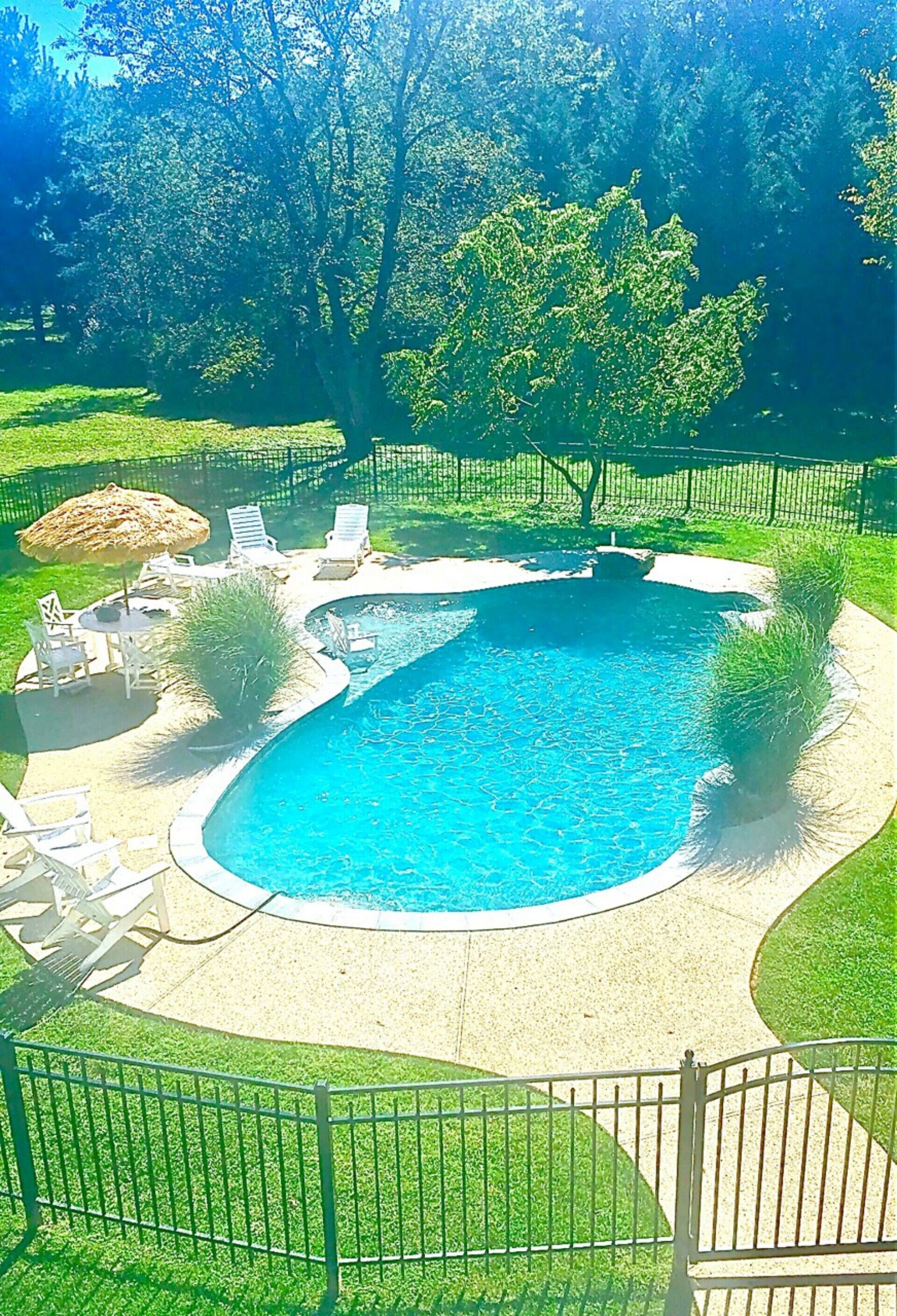 A backyard with a circular pool, surrounded by a fence, and equipped with lounge chairs and a small table.