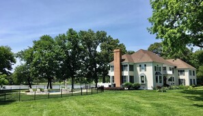 A two-story house with a brick chimney, surrounded by a well-maintained lawn and trees.