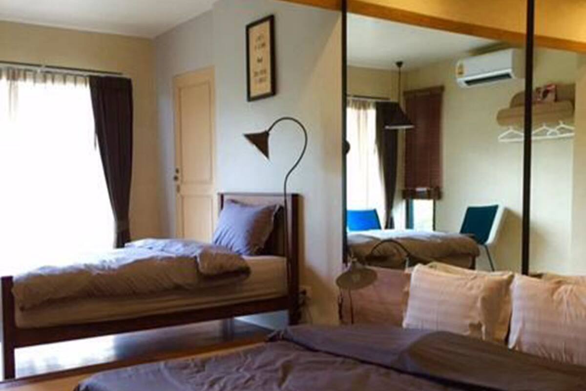 A room with two beds, a mirror, a desk, and a window with curtains.
