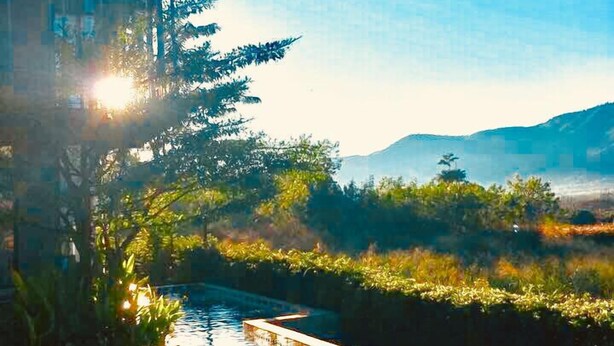 Uma piscina com água azul cristalina, rodeada por vegetação e uma montanha ao fundo.