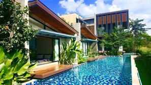 Un hotel moderno con piscina, zona de estar al aire libre y abundante vegetación.