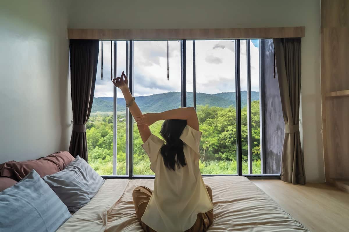 A room with a large window offering a view of a forested area.