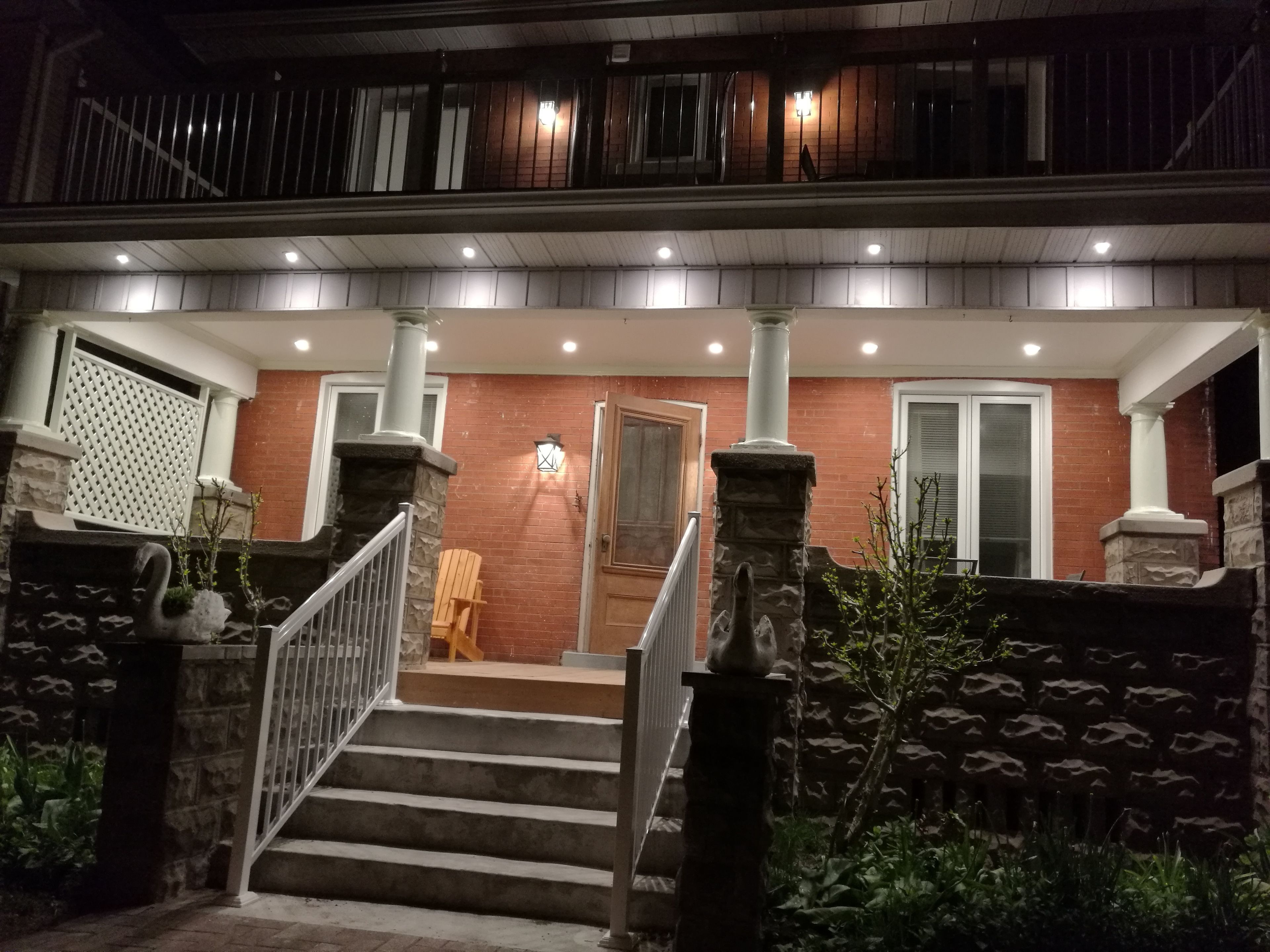 A two-story building with a brick facade, a wooden door, and a staircase leading to the upper floor.