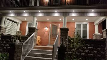 A two-story building with a brick facade, a wooden door, and a staircase leading to the upper floor.