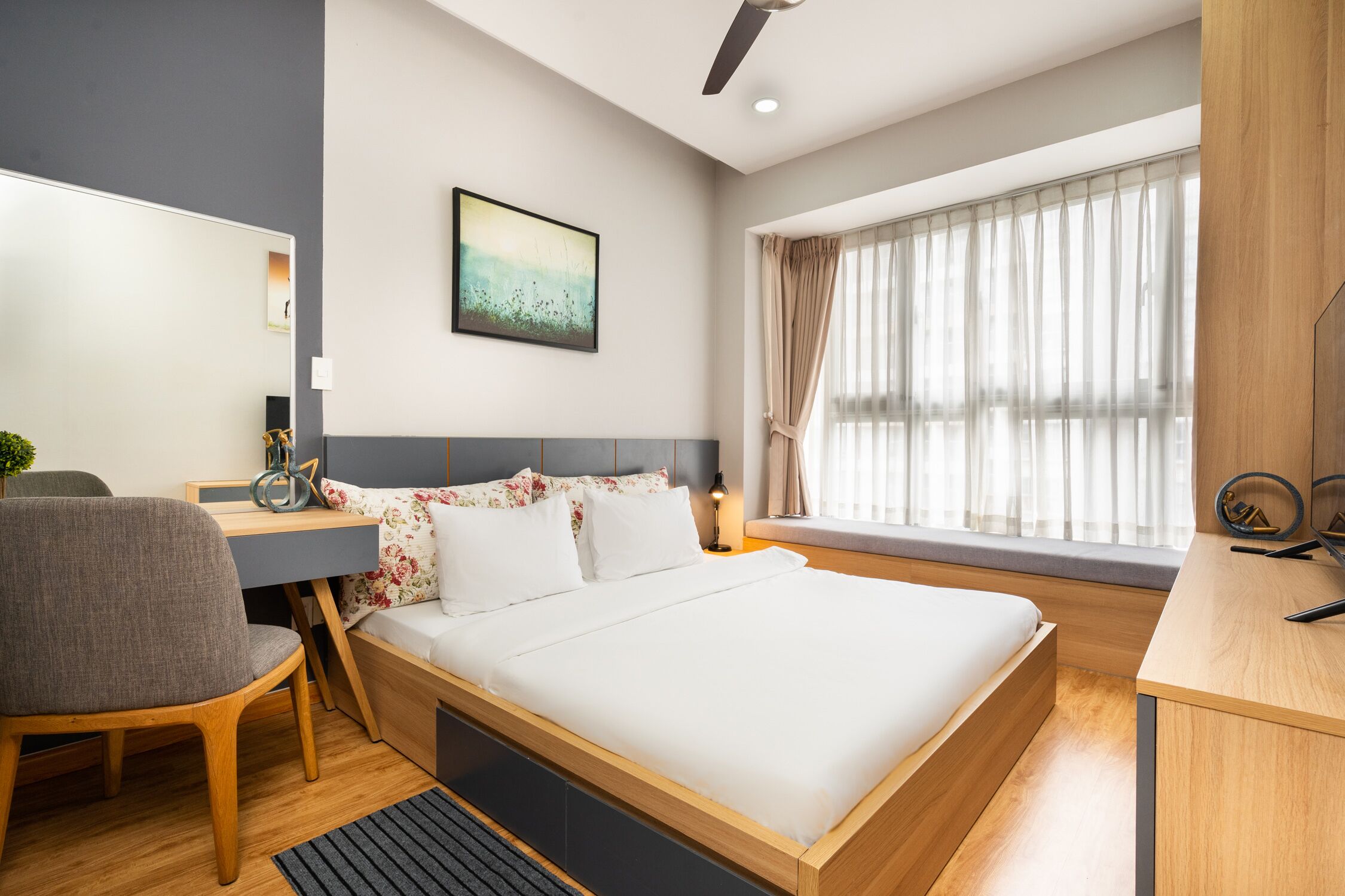 A modern bedroom with a wooden bed, a desk, a chair, and a window with curtains.
